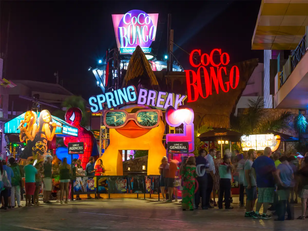 Iconic Cocobongo bar at night with neon lights and people around