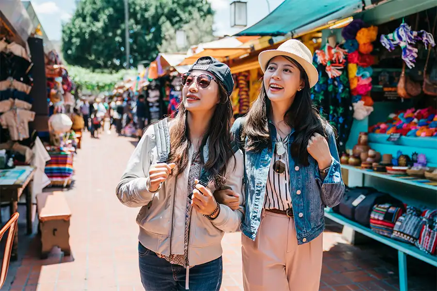 Two Asian tourist girls walking through a local market in Cancun